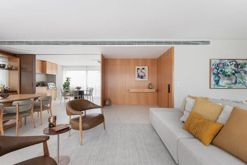 Projeto: Inovando Arquitetura | A lâmina de madeira natural percorre a marcenaria da sala, trazendo aconchego e sofistic